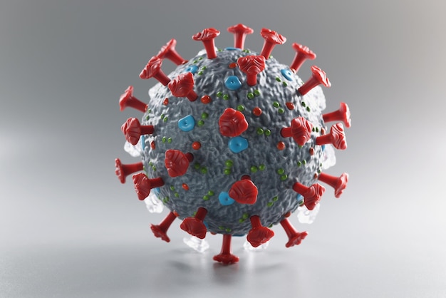 Plastic 3d model of coronavirus on a gray background, close-up. Search for a vaccine against omicron. Covid treatment. PCR test