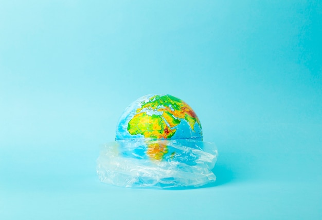 Plastic bag pollution concept. Earth globe in a plastic bag on a colored background. Plastic and waste pollution oceans, nature