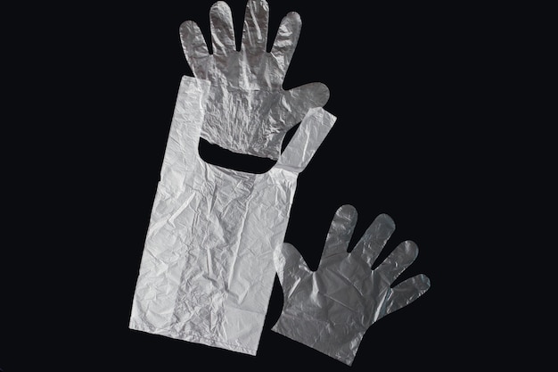 Plastic bag with handles, gloves, on a black background . Used plastic bag for recycling. Concept - ecology, planet pollution with plastic cellophane polyethylene.