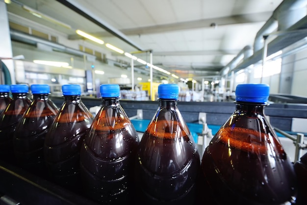 Plastic beer bottles on a conveyor belt in the background of a brewery