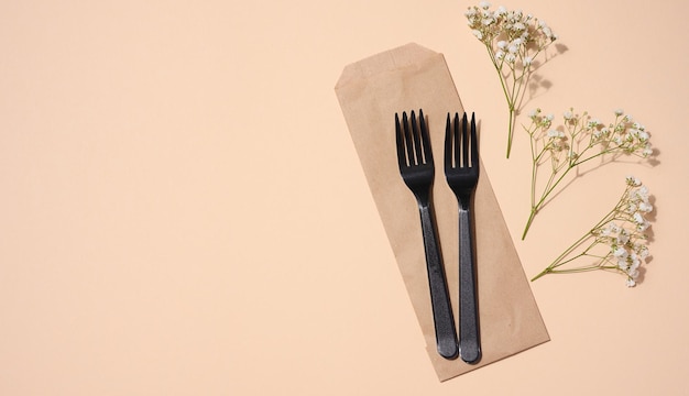 Plastic black forks on a beige background disposable picnic items top view