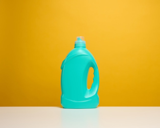 Plastic blue bottle with liquid detergent stand on a white table