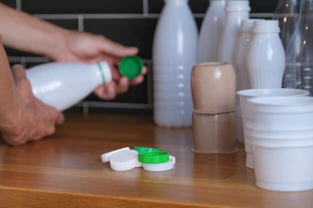 plastic bottle lids, bottles and food packaging are sorted by man in kitchen, recycling waste