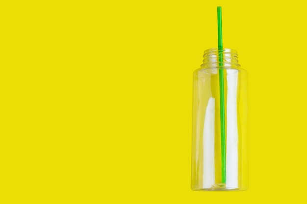 Plastic bottle with a cocktail tube on a yellow background