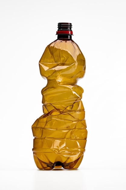 Plastic, crumpled brown soda bottle, isolated on white, close-up.