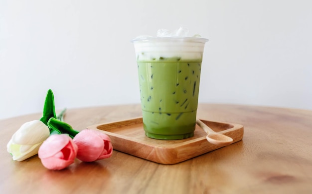 Plastic cup of iced green tea on wooden table