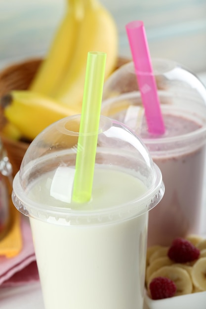 Plastic cup of milkshake on light wooden background