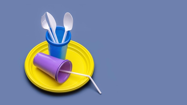 Plastic cutlery and disposable tableware on a gray background. Studio shot, close-up.