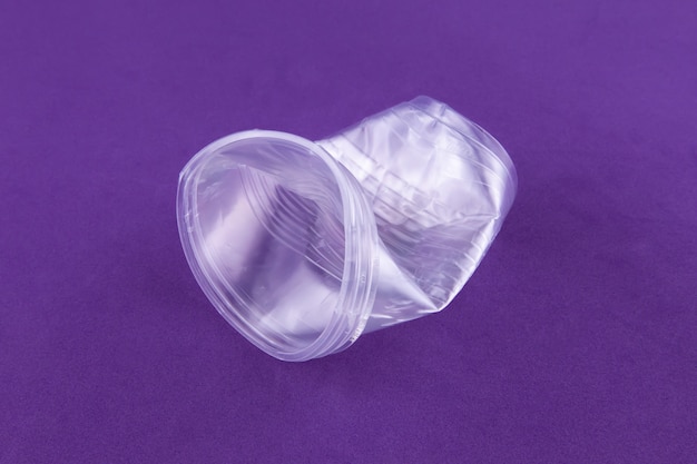 Plastic dishes crumpled cup on purple 