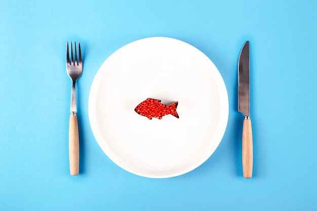 Plastic fish in a plate next to a knife and fork