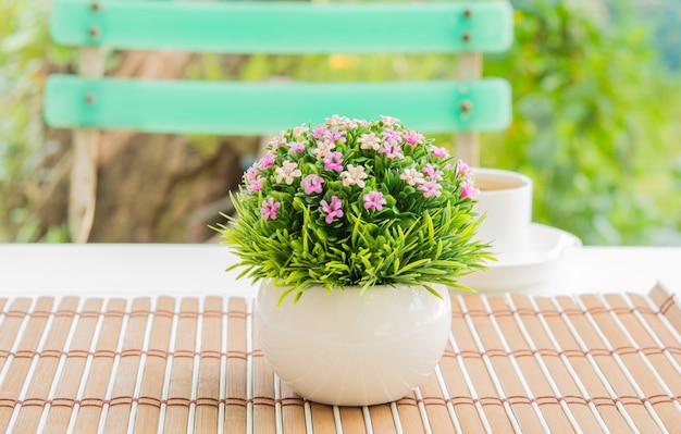 A plastic flower bouquet in a white spherical vase on a morning meal.