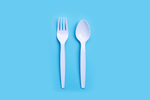 Plastic fork and spoon on blue background. Top view