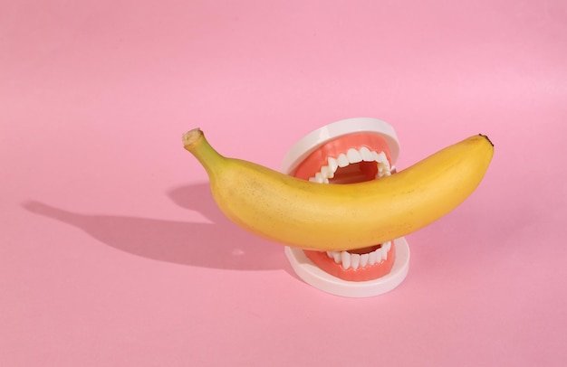 Plastic jaw with banana on pink background