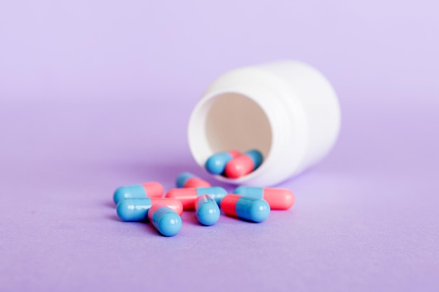 Plastic medicine bottle with capsules of pills on colored background Online pharmacy Painkiller medicine and antibiotic drug resistance concept Pharmaceutical industry