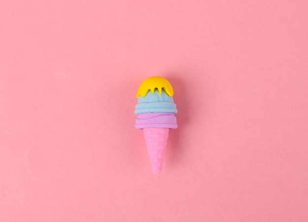 Plastic model of ice cream in cone on pink background Minimal food flat lay