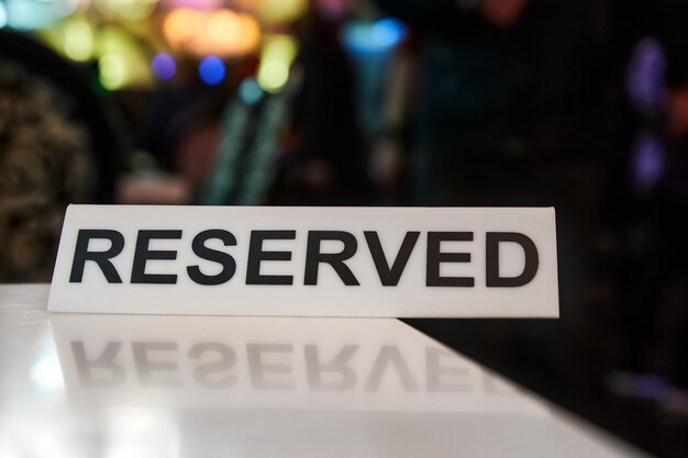 Plastic plaque with the inscription Reserved on the restaurant table.