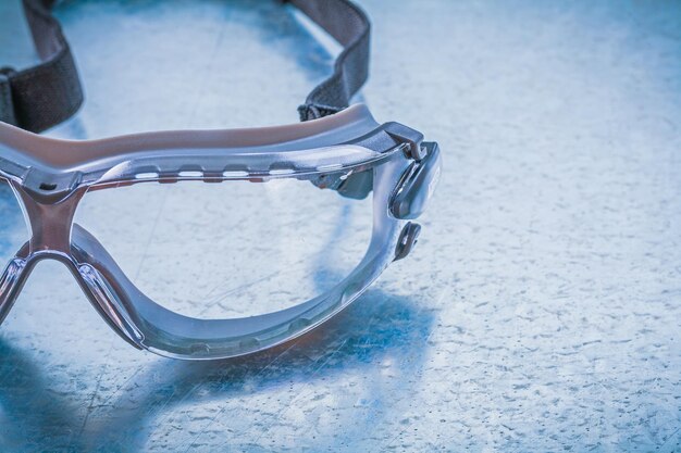 Plastic safety glasses on metallic background construction concept