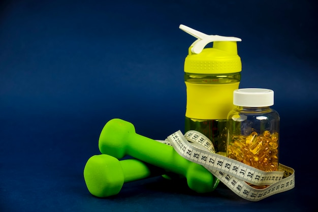 Plastic shaker, green dumbbells and a can of omega 3