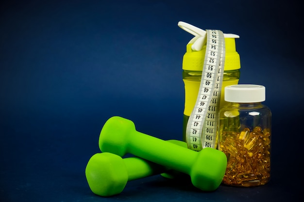 Plastic shaker, green dumbbells and a can of omega 3