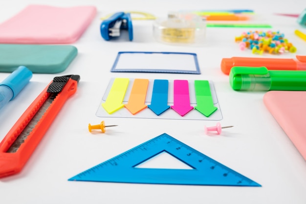 Plastic slavery. Blue ruler standing with colorful bookmarks with paper knife on white surface