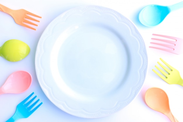 Plastic spoons and forks near white plate