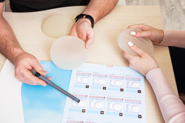 Plastic surgeon shows a sample set of a silicone implants for breast augmentation to a patient