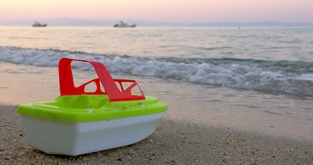 Plastic toy ship by the sea waves