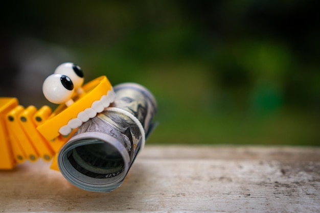 Plastic toy teeth with a roll of dollar banknote.