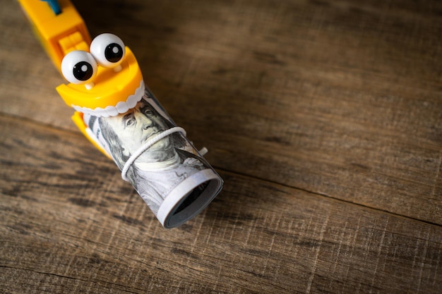 Plastic toy teeth with a roll of dollar banknote.