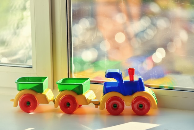 Plastic toy train with trailers on the window sill