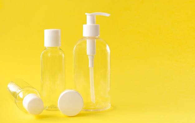 Plastic transparent cosmetic bottles with a white lid on a yellow background