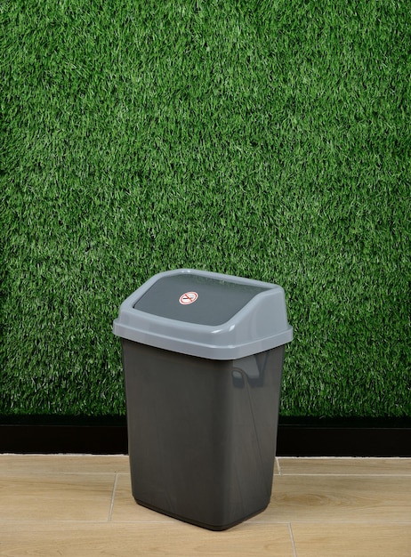 Plastic trash can on green background