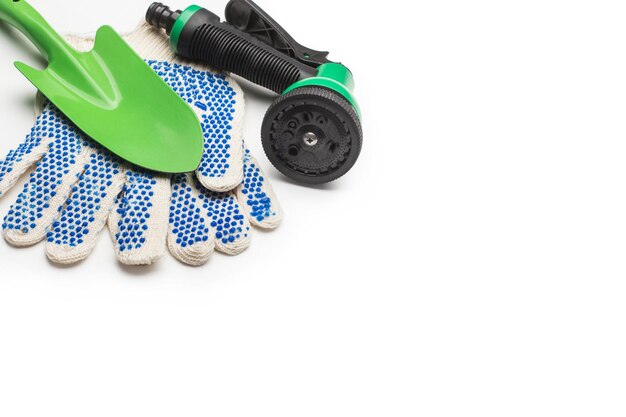 Plastic watering gun a spade and garden gloves on a white background with copy space