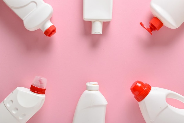 Plastic white bottles lie on a light pink background Layout of bottles with household chemicals for cleaning and disinfection of the room