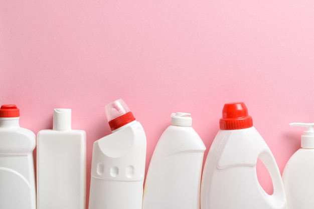 Plastic white bottles lie on a light pink background Layout of bottles with household chemicals for cleaning and disinfection of the room