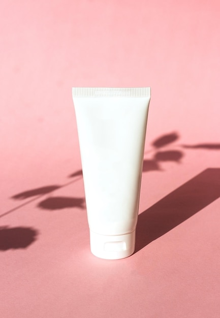 Plastic white tube for cream on pink background with shadow cosmetic ecofriendly product