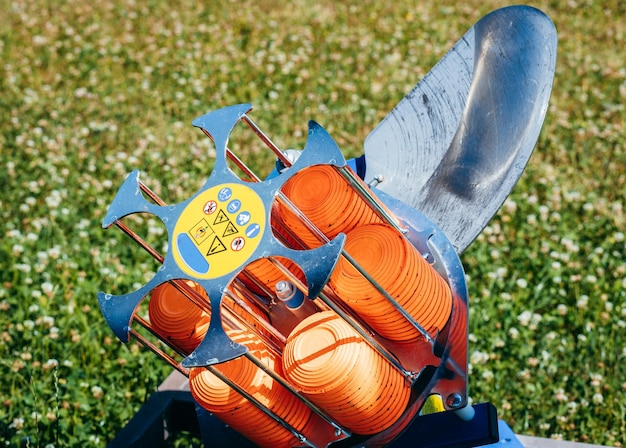 Plat machine with orange shooting plate for shootingground training on field with grass