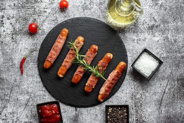 A plate of bacon sausages with bacon and wine on a table.