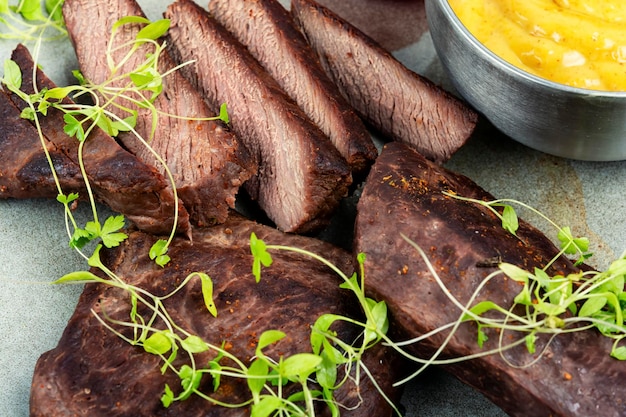 A plate of beef steaks with sprouts and mustard