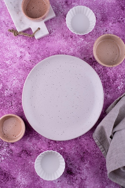 Plate bowls and cutting board on lilac background