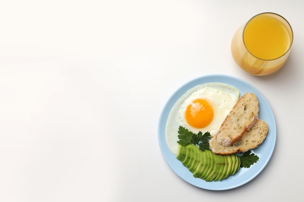 Plate of breakfast and glass of juice on white background