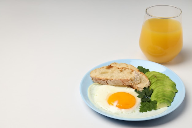 Plate of breakfast and glass of juice on white background