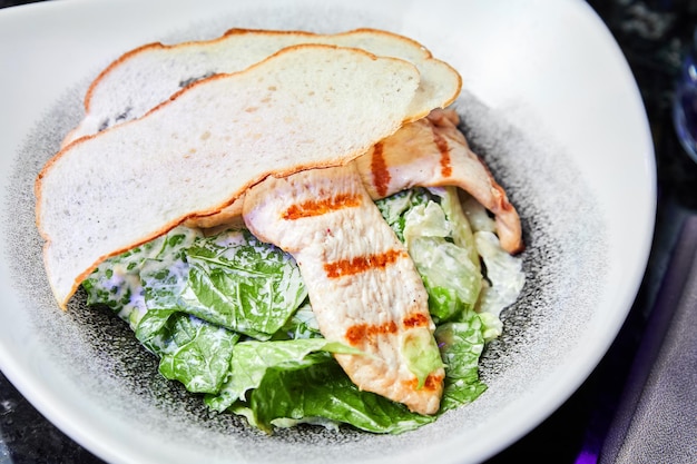 A plate of Caesar salad with chicken breast and parmesan