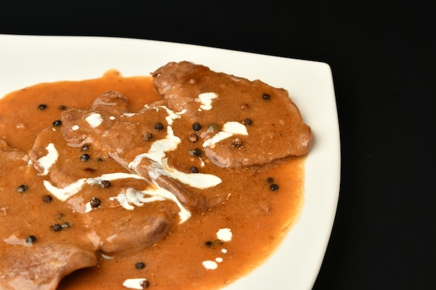 A plate of chicken curry with black and white spices