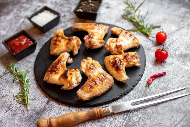 A plate of chicken wings with spices and herbs on a gray background.