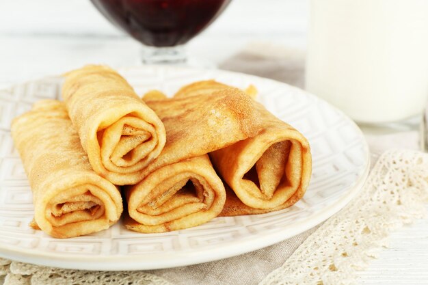 Plate of delicious pancakes and berry jam in glass bowl glass of milk on wooden background