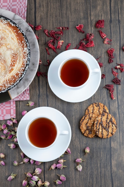 A plate of delicious pie with black tea placed on a wooden table .