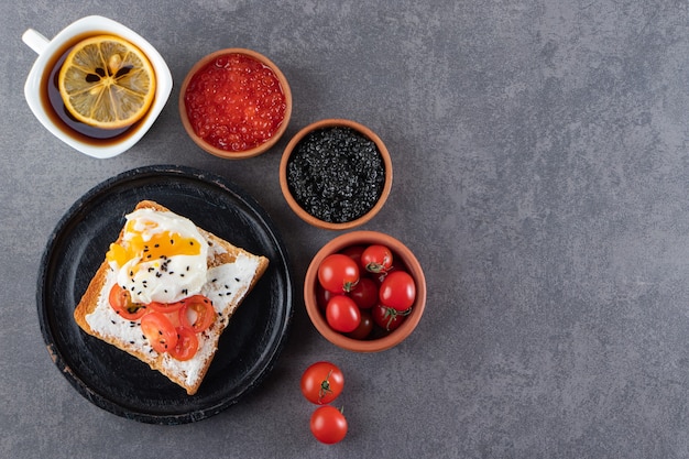 Plate of egg fried toast and cup of hot tea on stone table.