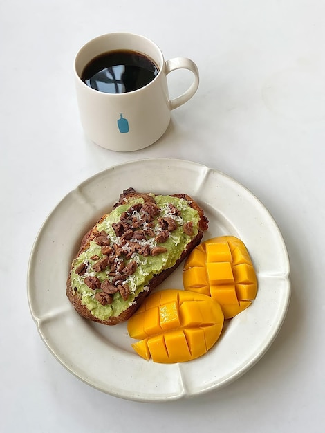 A plate of food with avocado and mango slices on it.