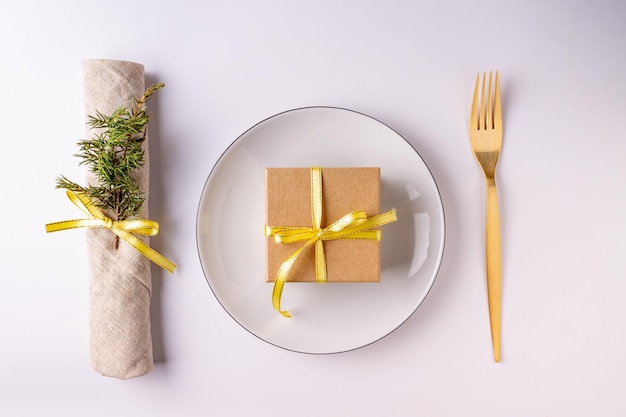 Plate, fork, napkin with a branch of a Christmas tree on a white background